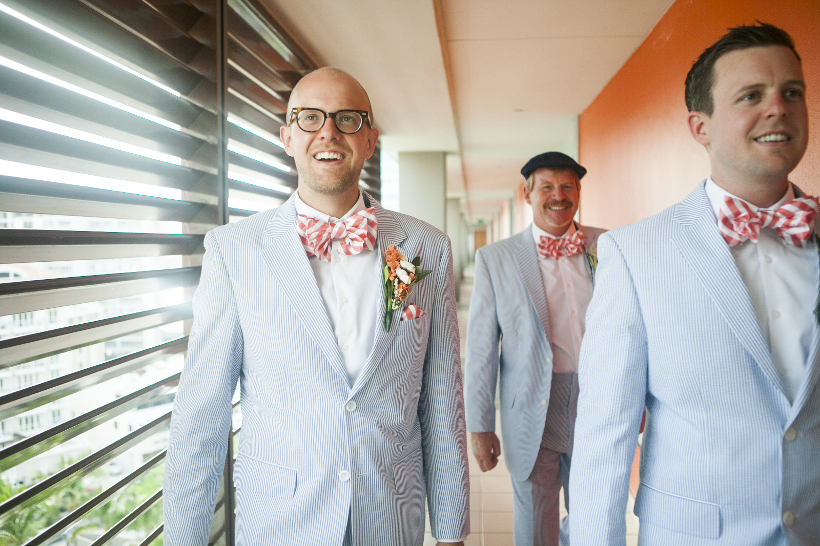 groom and groomsmen in blue seersucker suits and striped orange bow ties walk down the hall at la concha to the ceremony on the beach