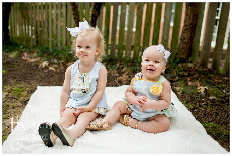 sisters smile together for a first birthday in spring clothes