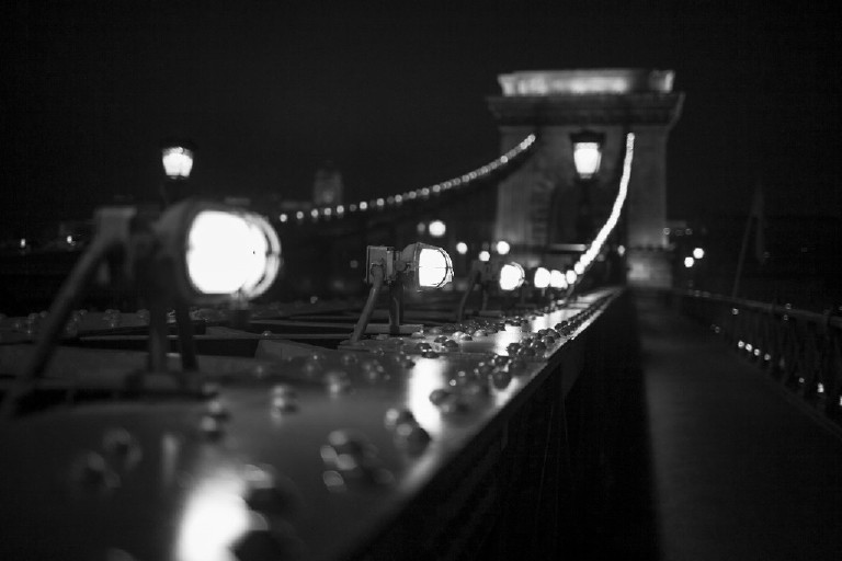 close up of light on chain bridge with arch in background