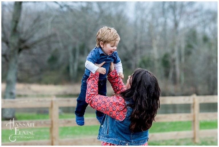 mom throws toddler son up into the air to make him smile