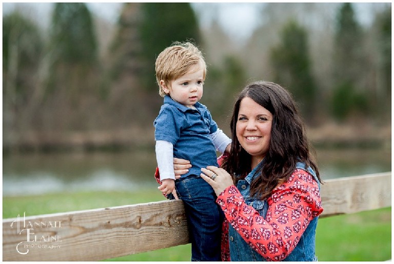 mom holds son on top of wooden fence at a lebanon farm