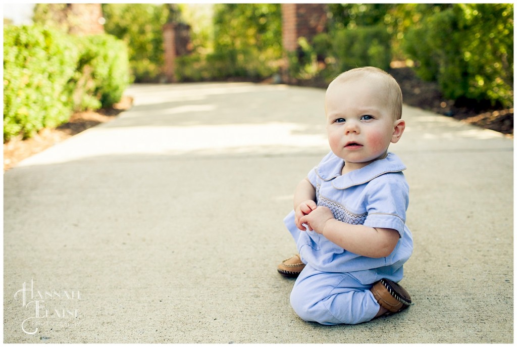 a boy kneels in a blue smocked jumper