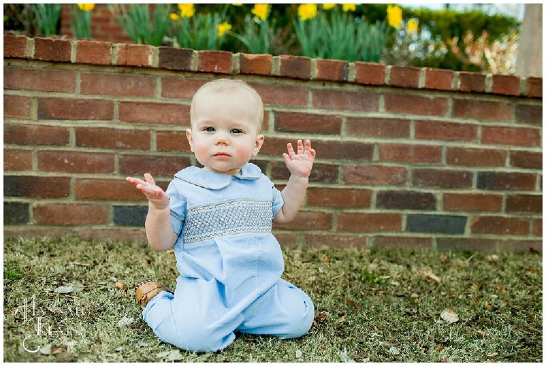 henry holds up his hands in mock wave with the daffodils