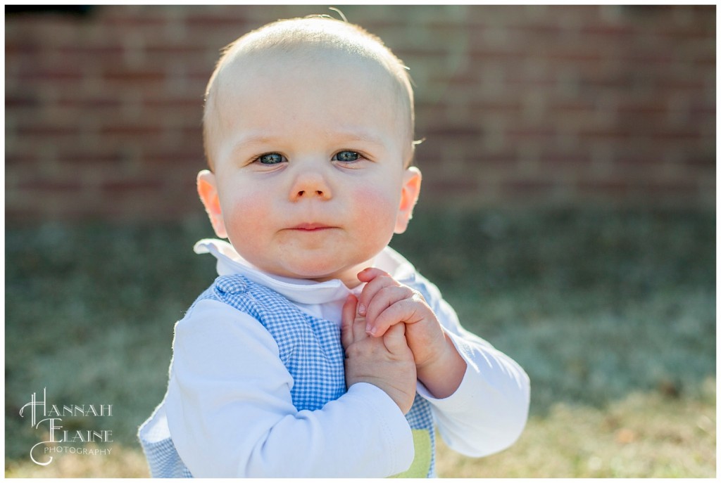 boy looks at camera with hands clasped