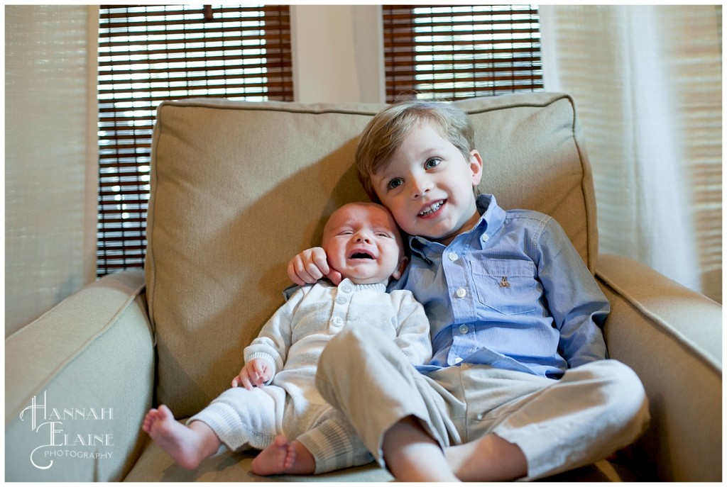 baby cries and big brother smiles in a big comfy chair