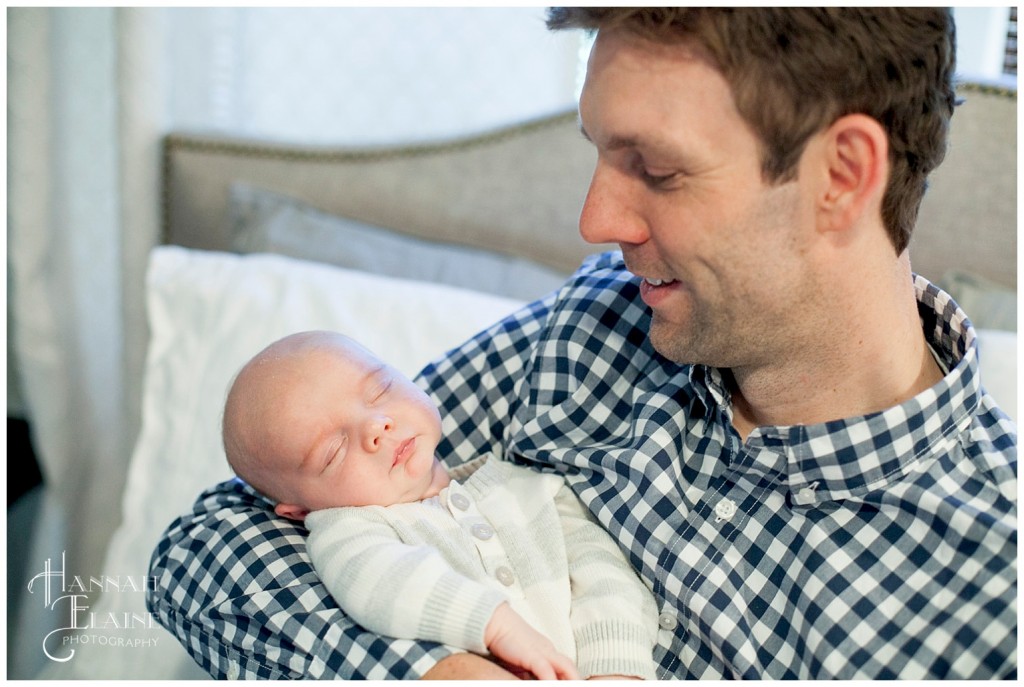 dad holds his sleeping new baby son