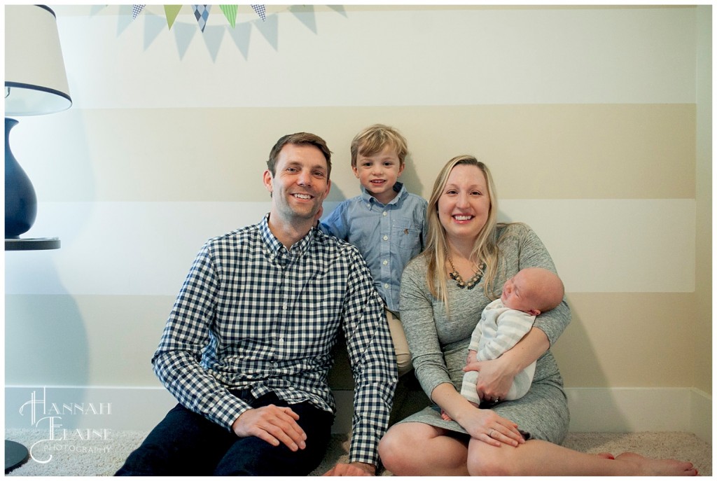 family takes photos in the nursery against the striped wall