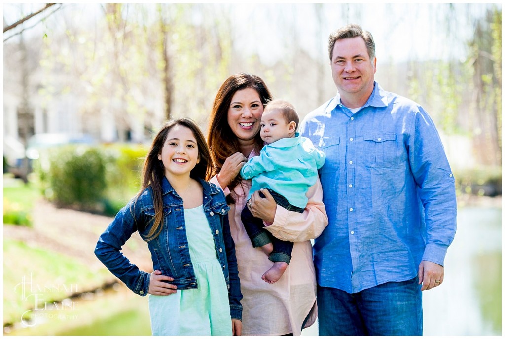 family poses next to weeping willow on the pond in franklin