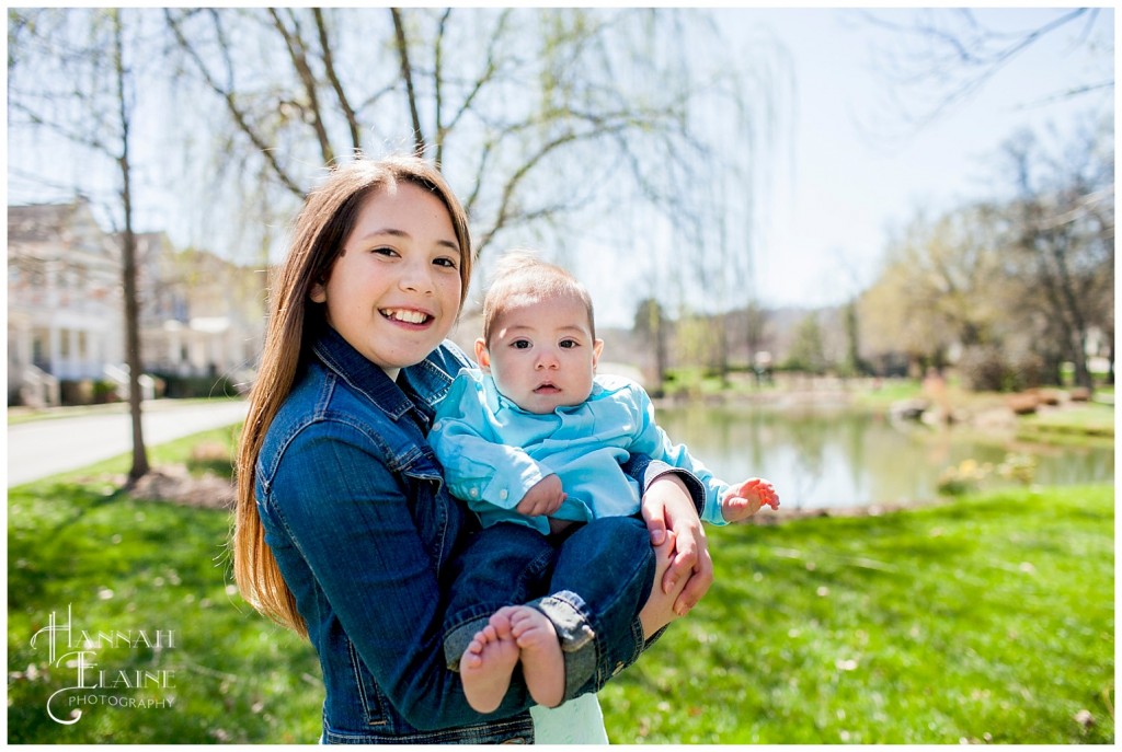 sister holds baby brother up for the camera