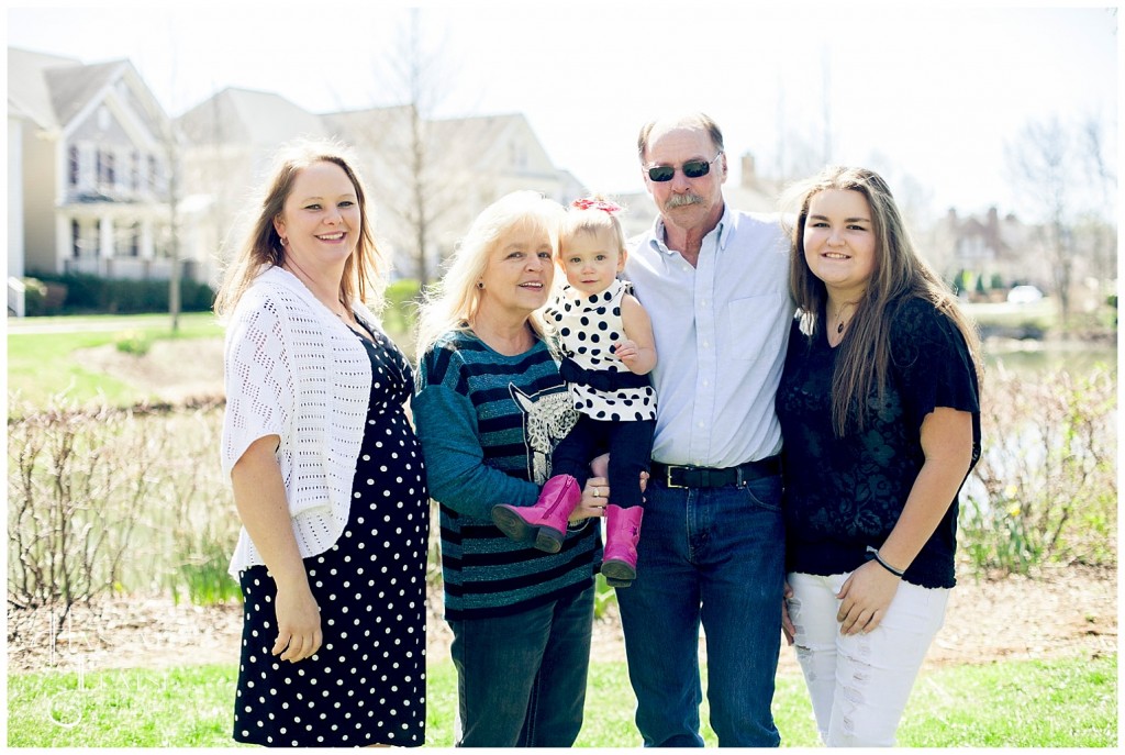 an extended family stands together in front of pearl street park pond