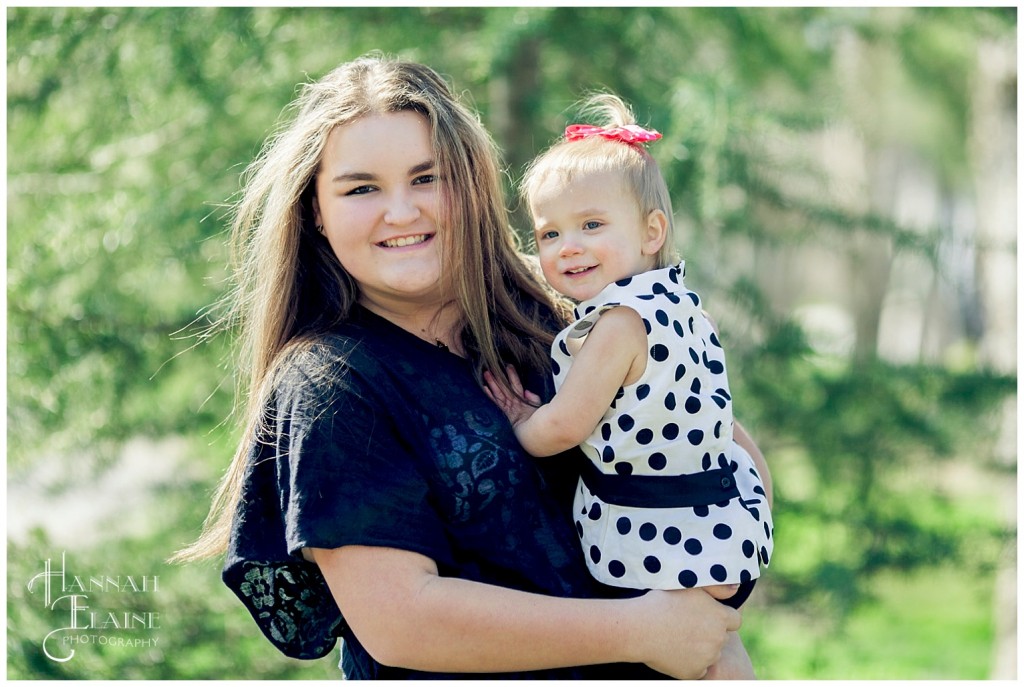 teenage girl holds her toddler sister at pearl street park