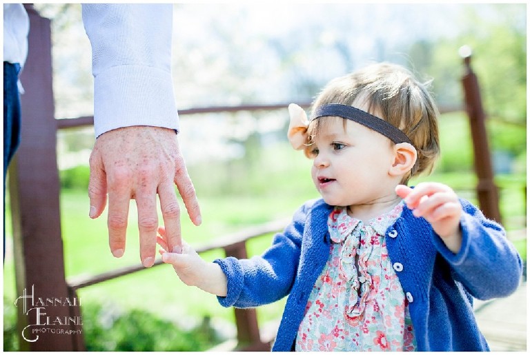 little girl grabs her daddy's finger for balance