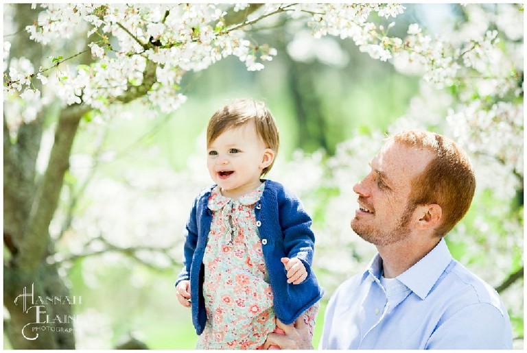 spring tree blooms behind a dad and daughter