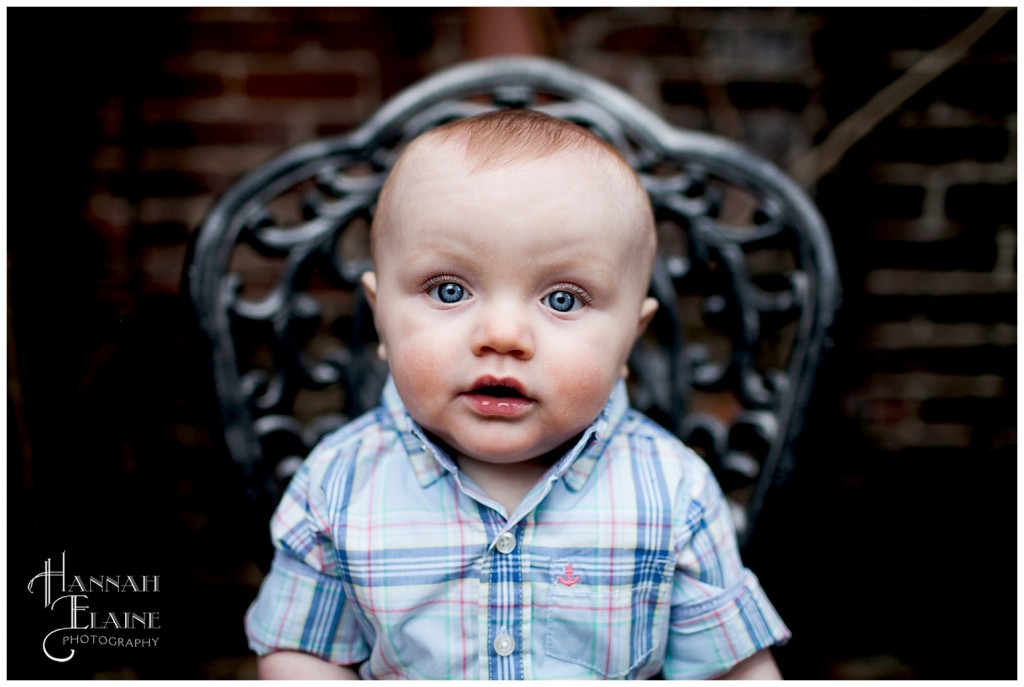 blue eyed baby boy sits on a wrought iron garden chair