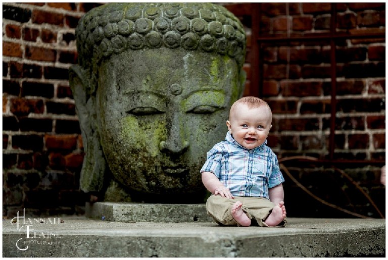 7 month old boy sits up in front of giant indian buddha statue