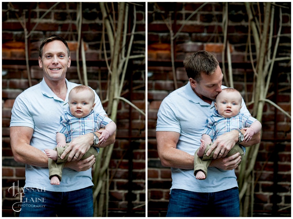 father and son cuddle against a rustic brick background