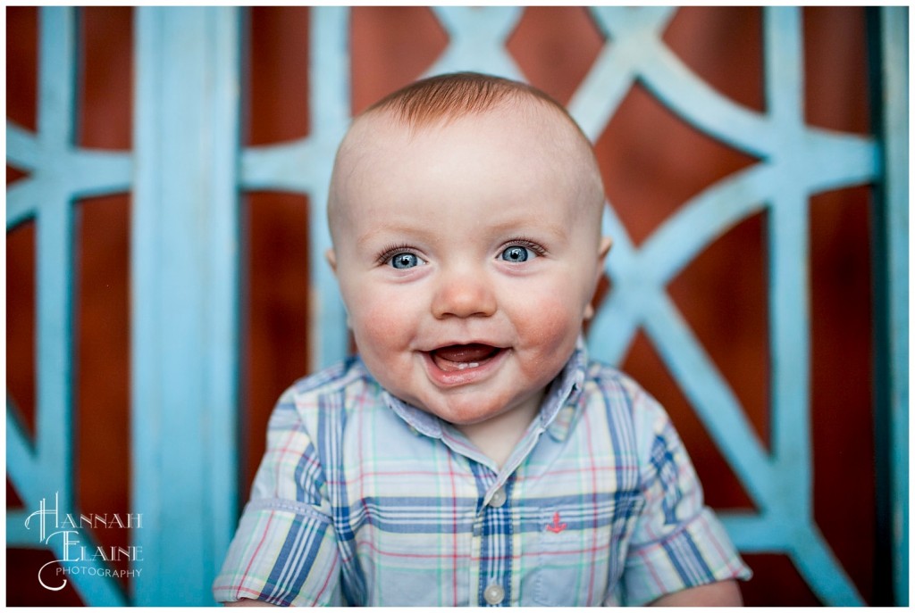 happy blue eyed boy giggles on a matching blue bench