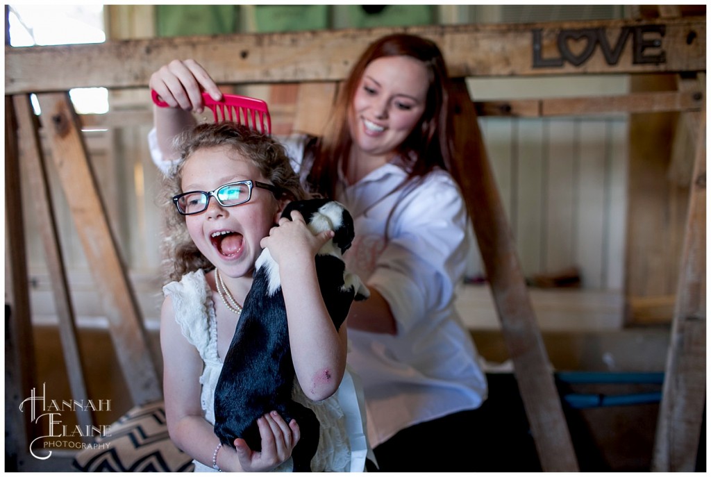 young flower girl holding boston terrier while getting hair done before the wedding 