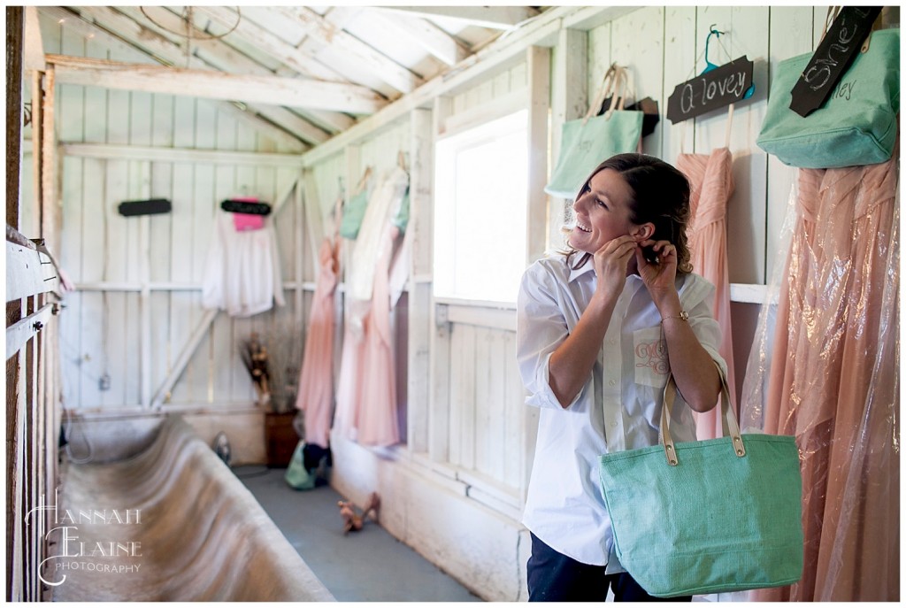 a bridesmaid puts on her earrings in the stable bridal suite