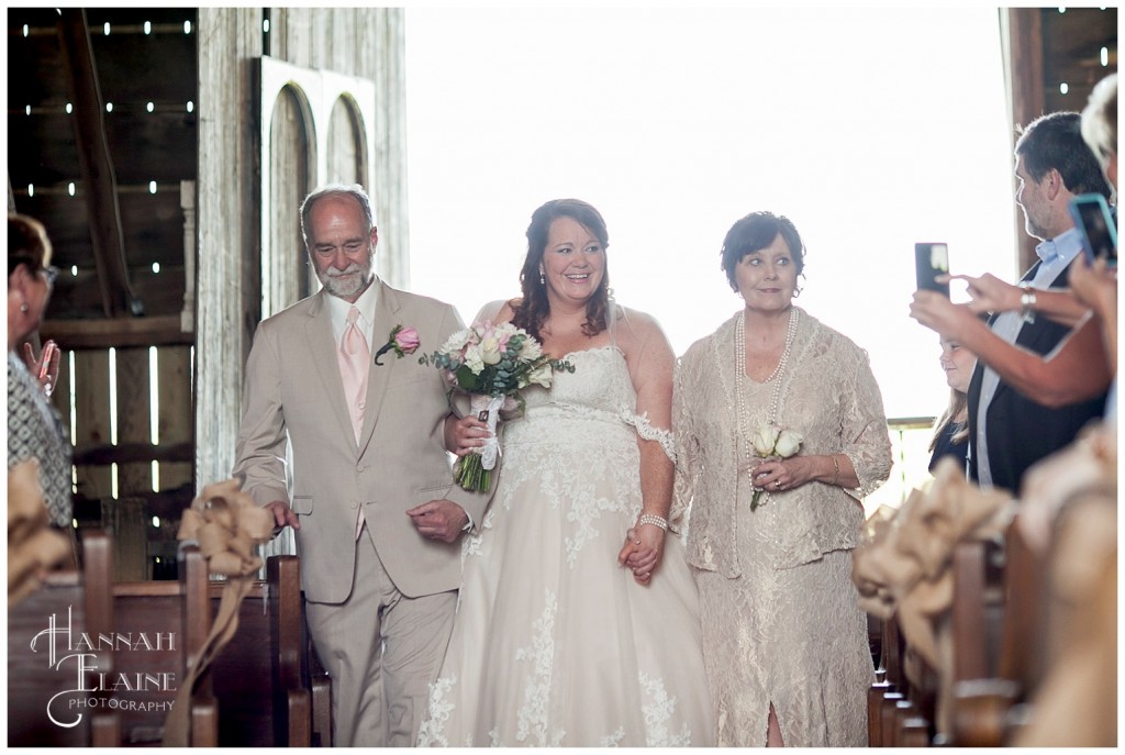 mom and dad walk their baby girl down the aisle