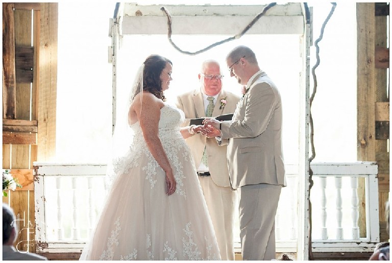 groom places the ring on his bride's finger during their wedding ceremony