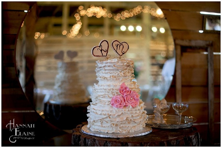 ruffled white wedding cake with initial heart toppers