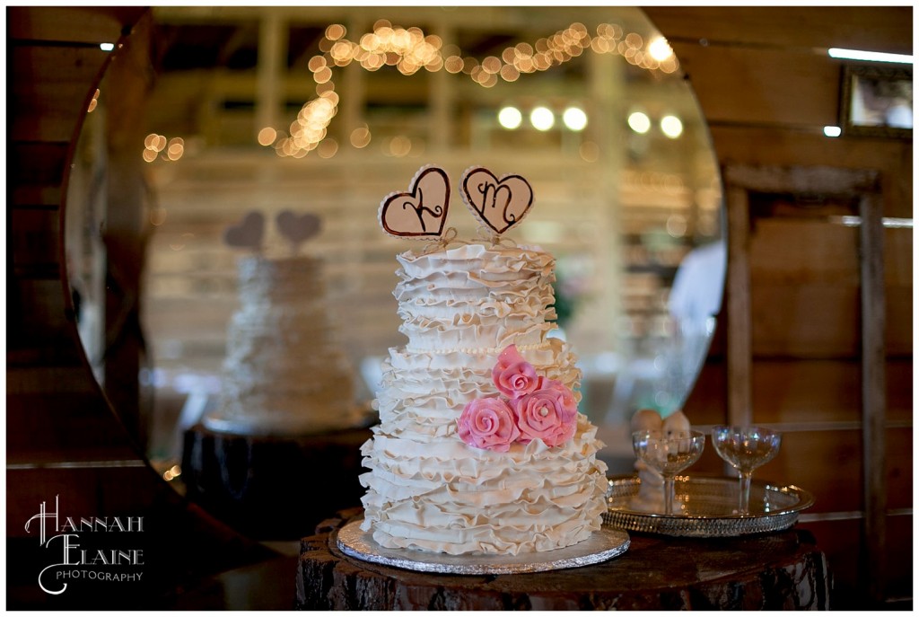 ruffled white wedding cake with initial heart toppers