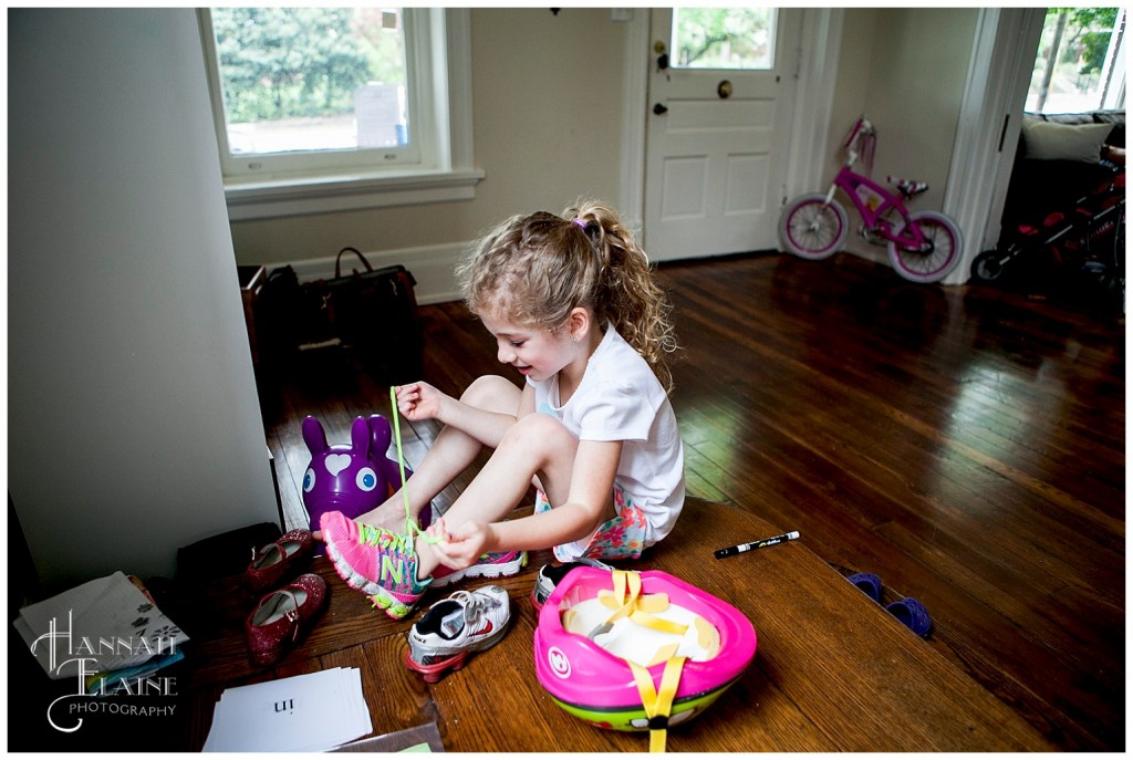 five year old puts her shoes on in preparation for a bike ride