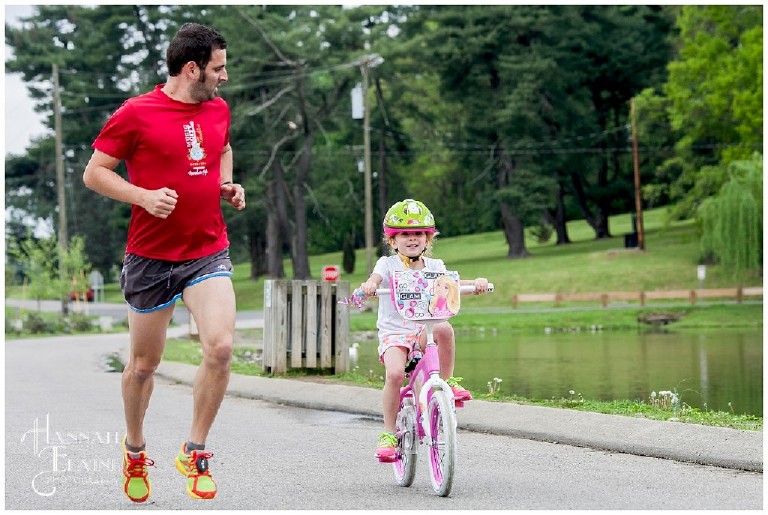 dad jogs next to daughter on her bike