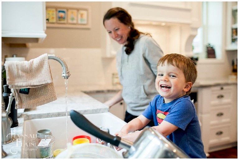 mom and son giggles while cleaning up in the kitchen sink