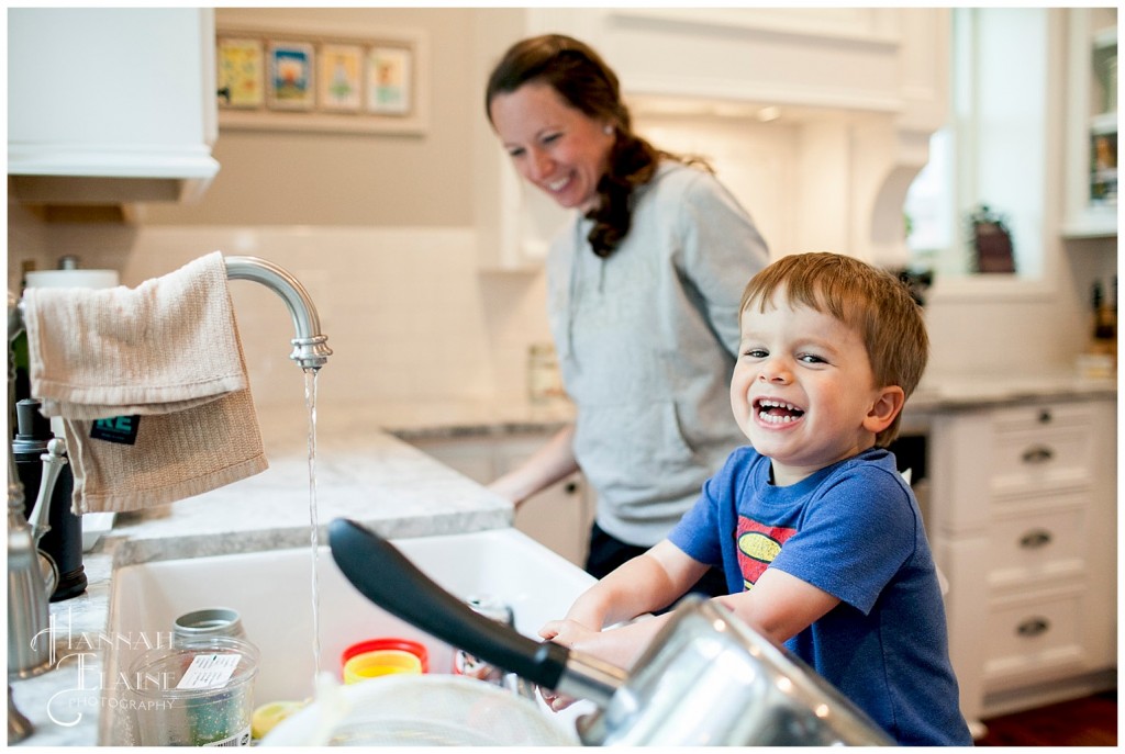 mom and son giggles while cleaning up in the kitchen sink