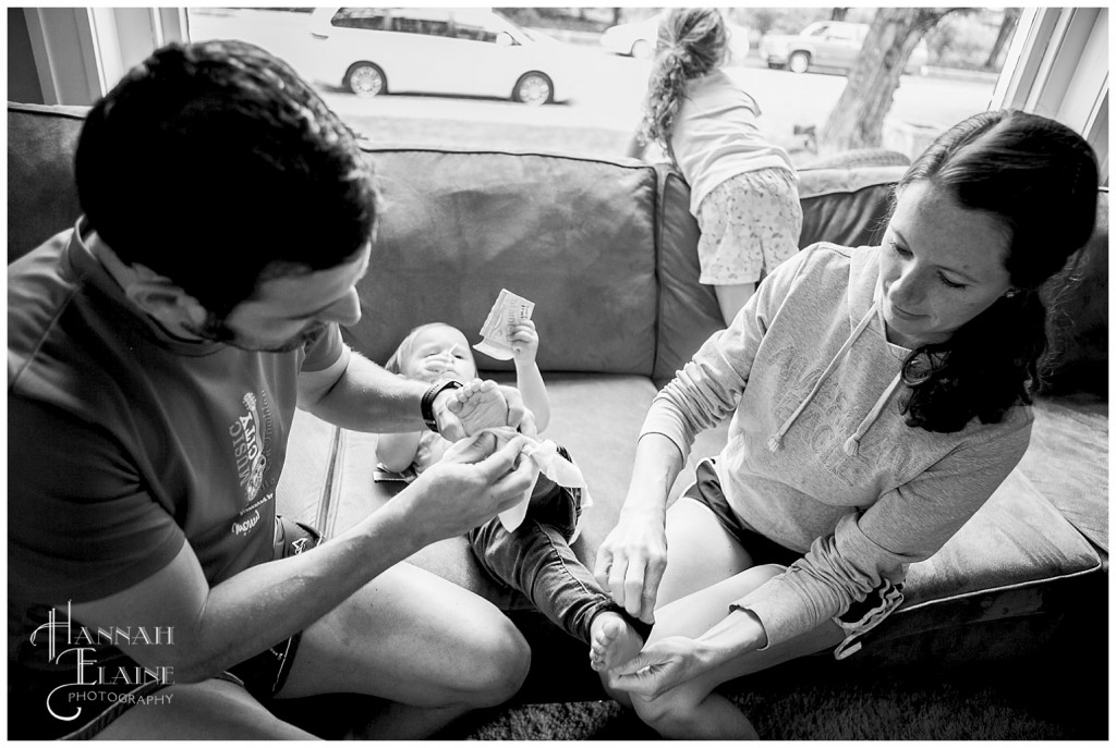 mom and dad each clean a baby's dirty feet with wet wipes