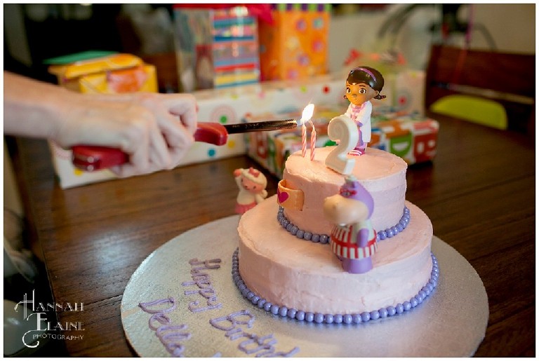 lighting the candles on a pink doc mcstuffins cake