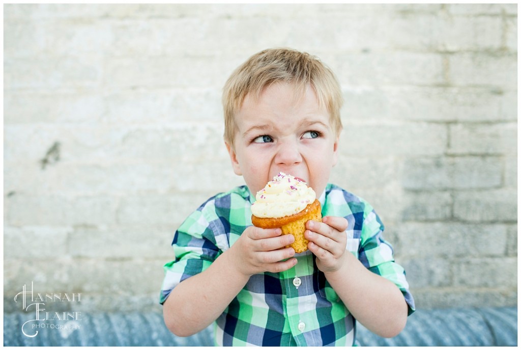 boy takes a giant bite out of a huge wholefoods cupcake