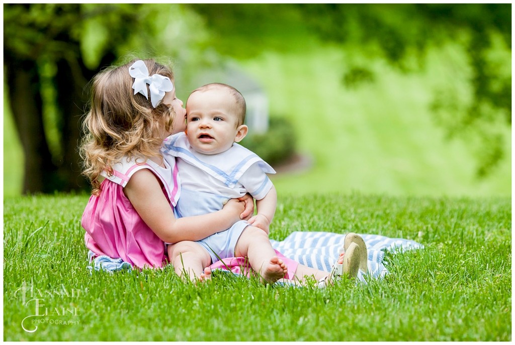 big sister gives her baby brother a kiss on the cheek