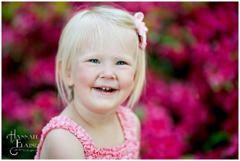 blond girl with pink bow in front of azaleas