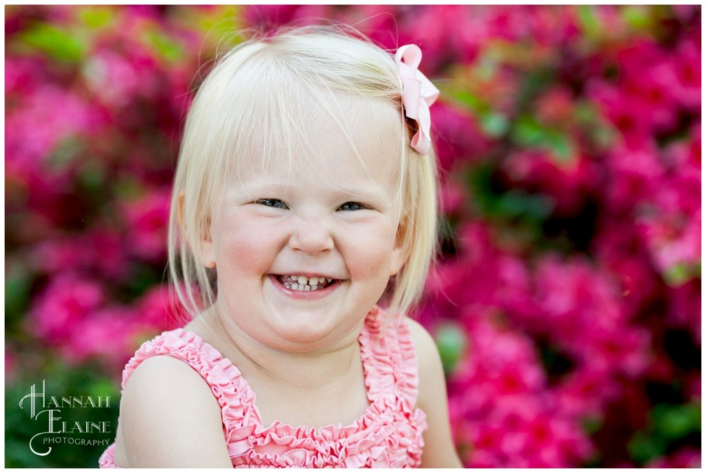 blond girl giggles in front of azaleas