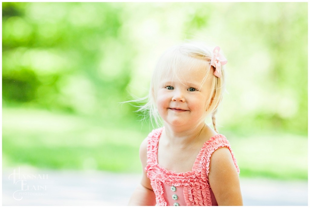 small blond girl in pink runs through the park