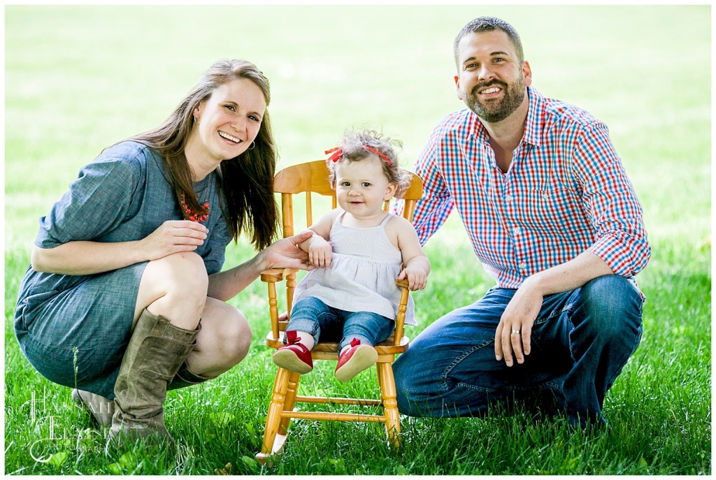 little girl sits in her rocking chair flanked by her parents