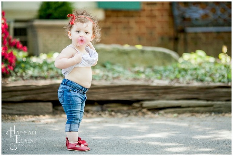 baby girl in red shoes shows her belly
