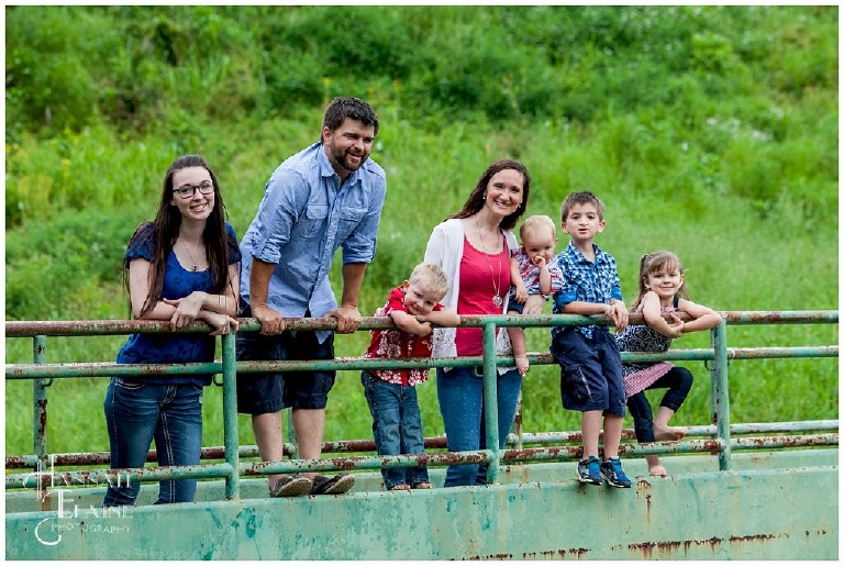 big family looks over the rail of a rustic green bridge