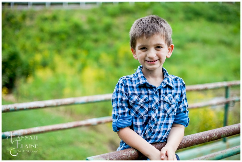 boy stands on rusty green bridge