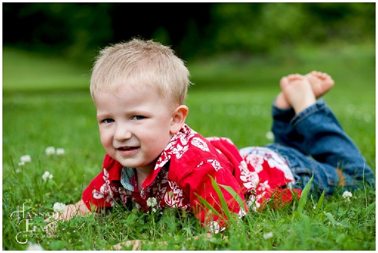 boy in red hawaiian shirt lays in the grass