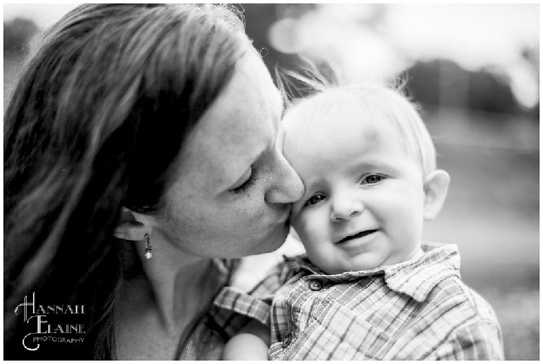 black and white photo of mom kissing little boy