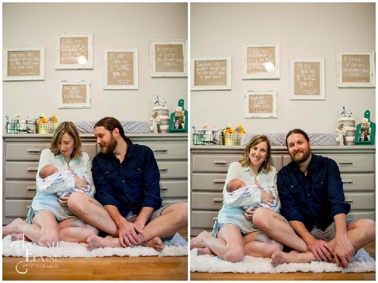 mom, dad and baby sit in front of the picture wall