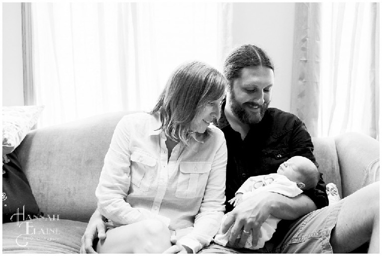 black and white image of family with new baby in front of window