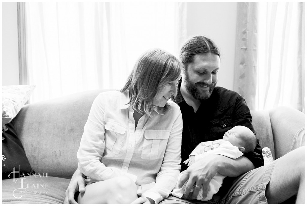 black and white image of family with new baby in front of window