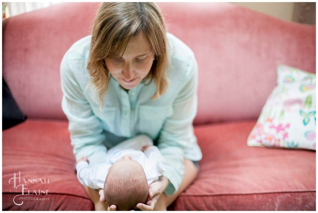 mom on pink couch looks at newborn baby