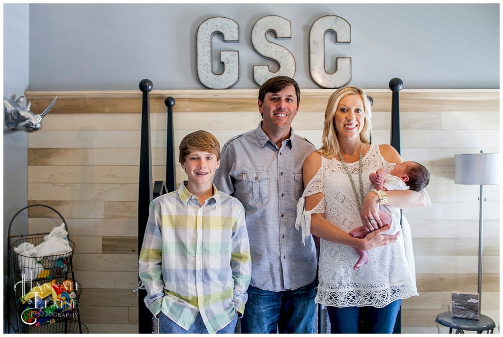 family stands in adorable nursery with new baby