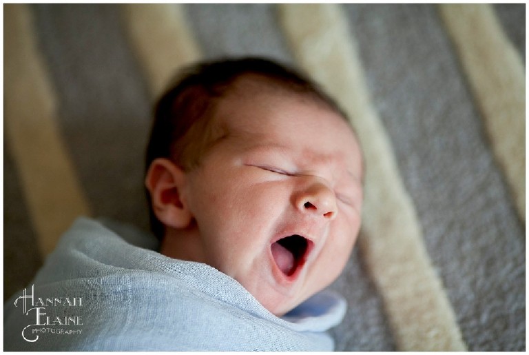 newborn boy in blue cheesecloth yawns
